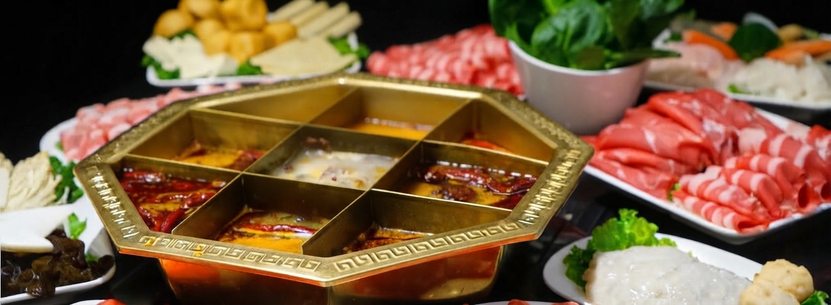 Hotpot surrounded by fresh meats, vegetables, and sharing platters